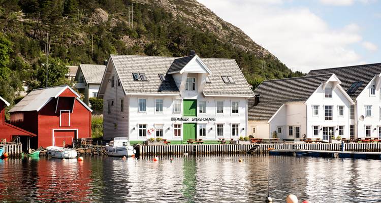 Des maisons riveraines en bois blanc et des abris à bateaux se reflétant dans les eaux calmes du port