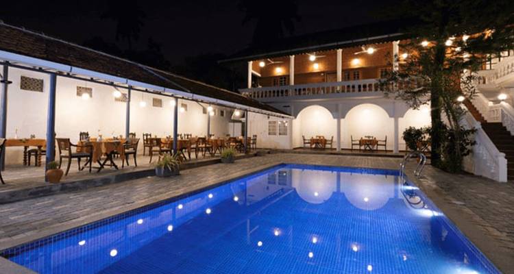Hôtel de charme historique avec piscine et espace de restauration en plein air subtilement éclairé la nuit.