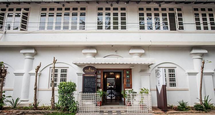 Charmant bâtiment de style colonial blanc avec une porte cintrée et un menu sur tableau noir à l'extérieur.
