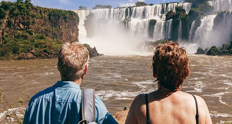 Twee reizigers bewonderen de machtige Iguazu Falls vanuit een uitkijkpunt aan de rivier.