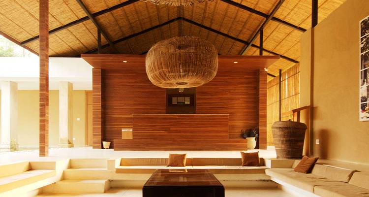 Hall d'hôtel élégant en bois et bambou avec éclairage chaleureux, luminaire tissé et sièges rembourrés.