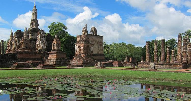 Les ruines d'un ancien temple en brique et les colonnes debout se reflétant dans un étang de lotus sous un ciel bleu