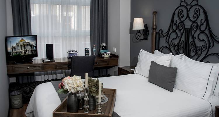 Elegant hotel bedroom featuring wrought iron headboard, desk, and cozy gray accents