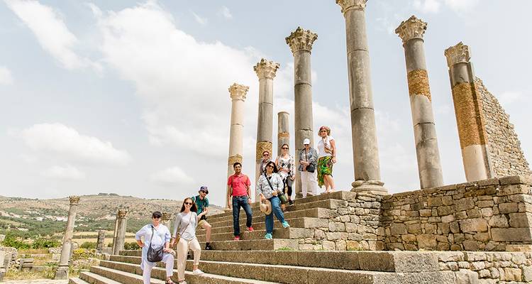 Toergroep verkent oude Romeinse zuilen en stenen trappen van de ruïnes van Volubilis