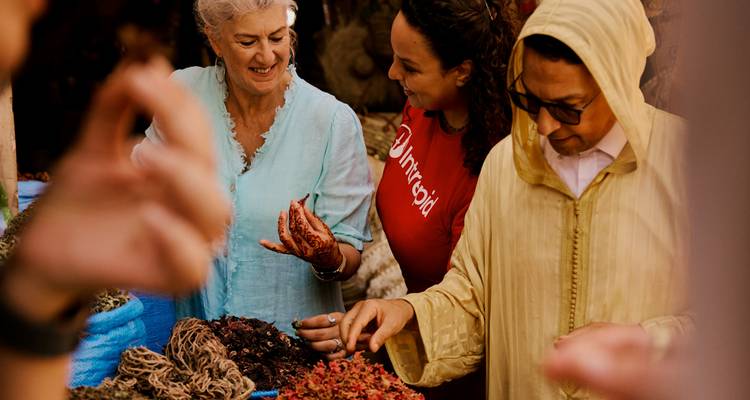 Marktverkoper toont geurige kruiden aan geboeid reiziger in rood Intrepid shirt