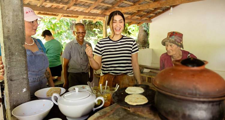 Travellers laugh while making traditional flatbreads in an open-air Sri Lankan kitchen