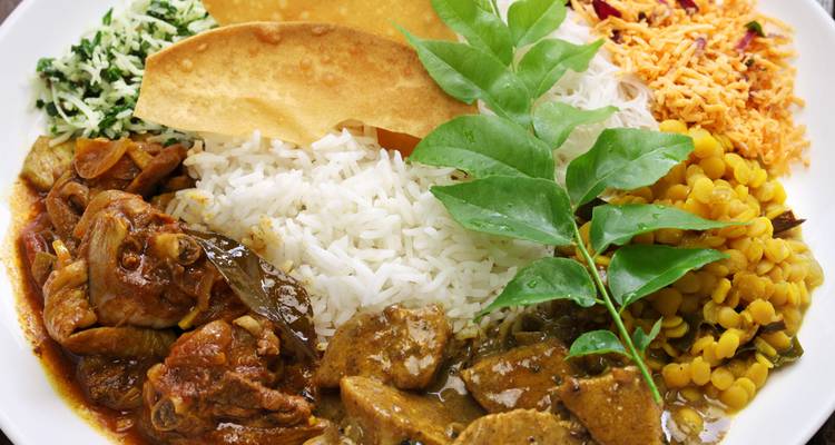 A colourful Sri Lankan rice and curry platter with assorted vegetables, papadum and meat curries.