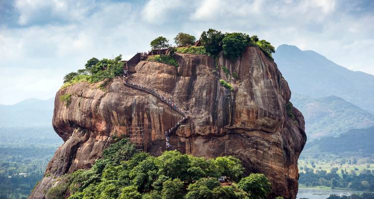 The massive Sigiriya rock fortress with a winding staircase carved into the cliff.