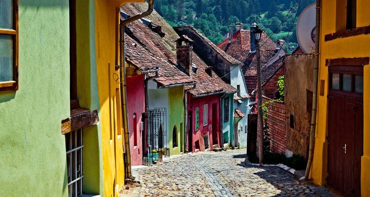 Kopfsteinpflastergasse mit leuchtend bemalten mittelalterlichen Häusern im historischen Zentrum von Schäßburg.