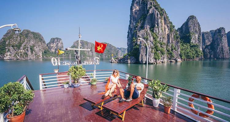 Deux voyageurs se détendent sur le pont d'une croisière surplombant les formations calcaires spectaculaires de la baie d'Halong.