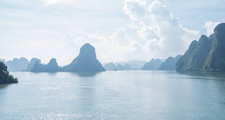 Vue matinale brumeuse sur les eaux calmes et les pics karstiques de la baie d'Halong.
