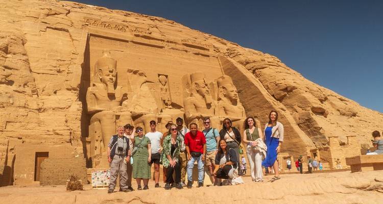 Group poses in front of the colossal statues of Abu Simbel under a clear blue sky.