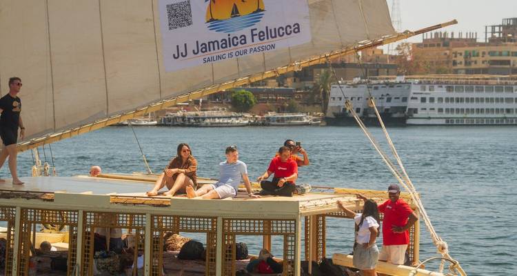 Travellers lounge on the roof of a felucca with sails down while moored on the Nile.