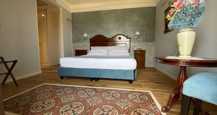 Chambre d'hôte confortable avec tête de lit bleu-vert, tapis en carrelage à motifs et plancher en bois dans un hôtel-boutique.