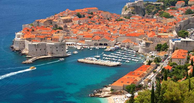 Aerial view of Dubrovnik’s walled Old Town jutting into the azure Adriatic Sea.