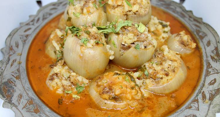Traditional Bosnian stuffed onions served in a rich tomato sauce on ornate metalware.