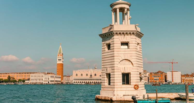 Petit phare dans la lagune de Venise avec le Campanile de Saint-Marc visible de l'autre côté de l'eau.