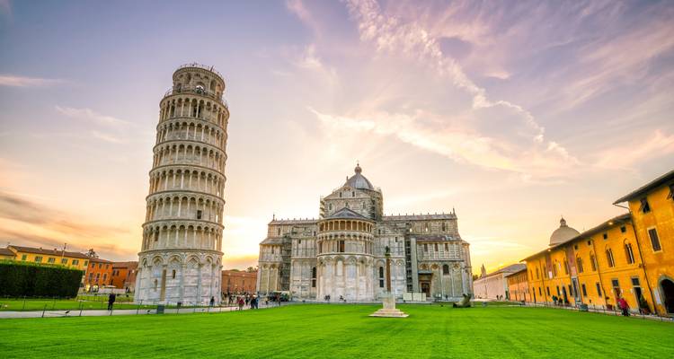 La Torre Inclinada y la Catedral de Pisa brillan al atardecer sobre los cuidados céspedes verdes.