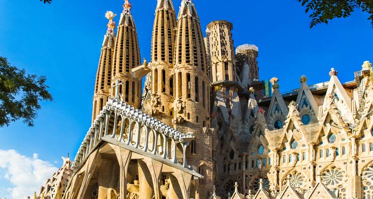 Primer plano de las torres esculpidas de la Sagrada Familia bajo un cielo azul brillante de Barcelona.
