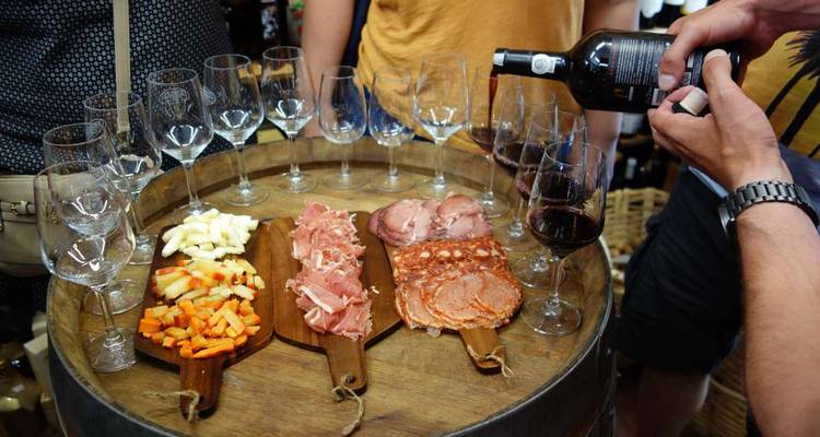 Des vins et des viandes de tapas locales arrangés sur des planches en bois autour d'un tonneau en chêne lors d'une dégustation en cave.