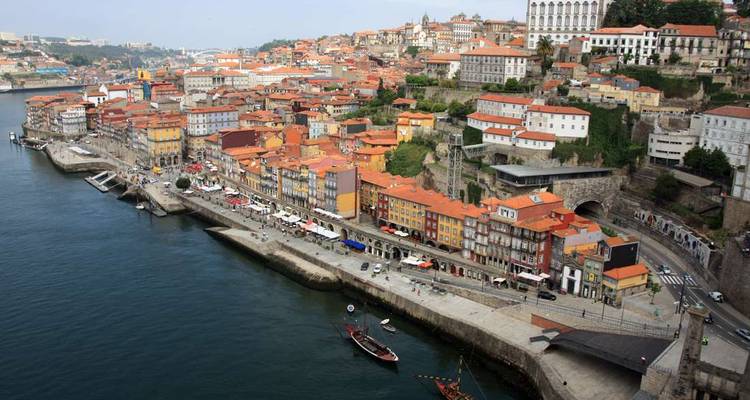 Vue aérienne du quartier riverain coloré de Porto épousant le fleuve Douro avec ses bateaux classiques et ses ponts.