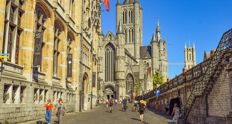 Catedral gótica de piedra y edificios históricos a lo largo de una calle empedrada con peatones.