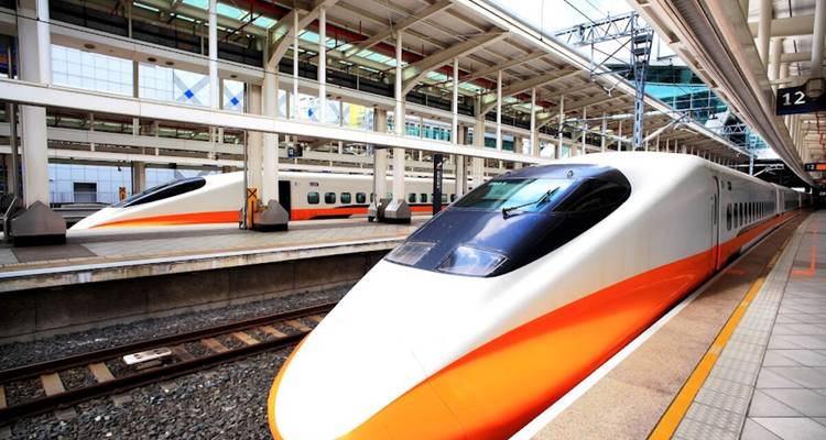 Trenes bala Shinkansen modernos de color blanco y naranja esperando en una plataforma de estación limpia y techada.