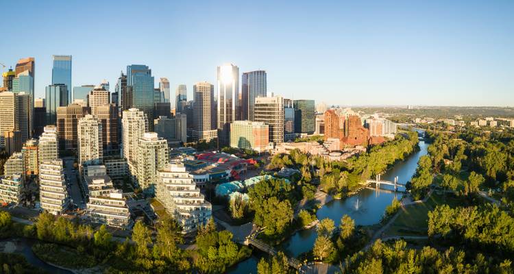 Lumière panoramique du lever de soleil surplombant la ligne d'horizon vitrée de Calgary et son fleuve sinueux, capturée d'en haut par une journée dégagée.