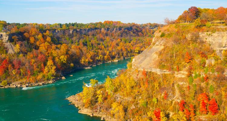 Lebendiges Herbstlaub entlang einer Schlucht mit Blick auf einen türkisfarbenen Fluss in Ontario, Kanada.