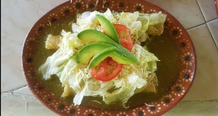 Traditionelles mexikanisches Gericht mit Avocado, Tomate und gehacktem Salat, serviert auf einem Tonteller