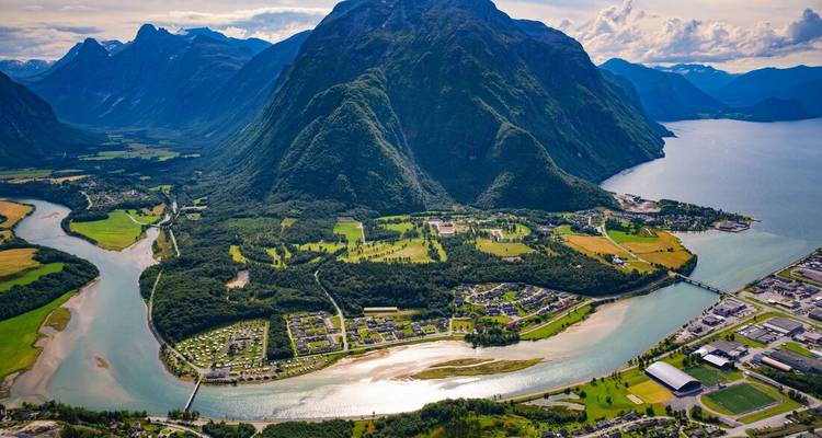 Vue aérienne d'une vallée norvégienne luxuriante entourée de montagnes imposantes et d'une rivière sinueuse.
