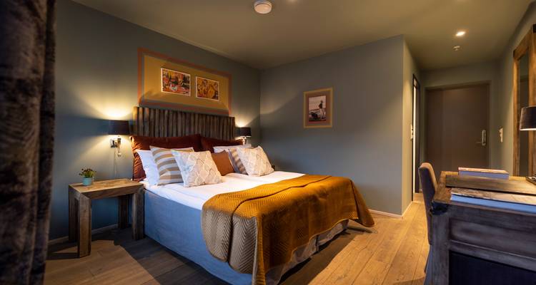 Chambre d'hôtel chaleureuse et élégante avec lits jumeaux, touches en bois et éclairage doux.