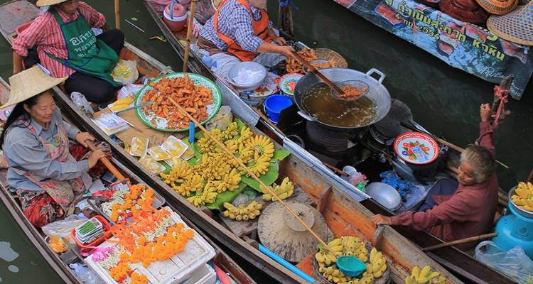 Les vendeurs sur les bateaux en bois vendent des bananes, des collations et des aliments frits à un canal de marché flottant coloré.