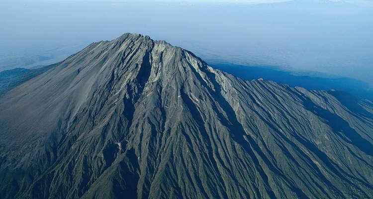 Luchtfoto van bovenaf van de onregelmatige vulkanische kegel en bergkammen van de Berg Meru, mooi uitgelicht door het heldere ochtendlicht.