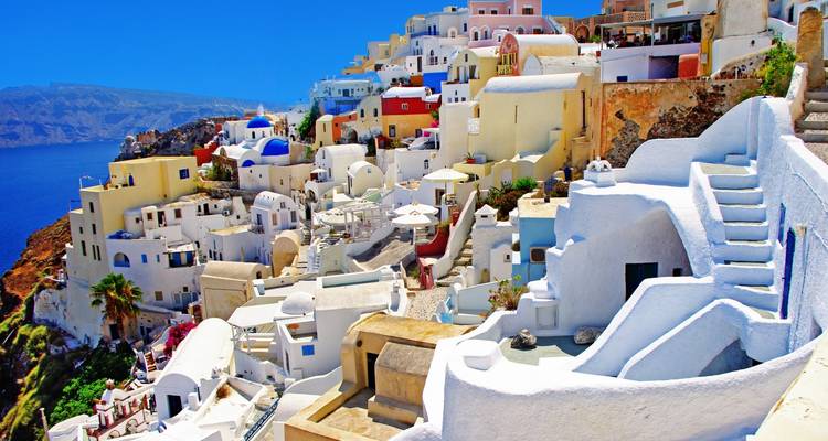 Las casas iluminadas en los acantilados y las cúpulas de Santorini descienden hacia el profundo mar Egeo azul