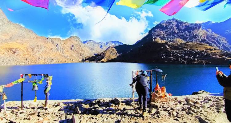 Les pèlerins accomplissent des rituels auprès du lac turquoise de Gosainkunda, bordé par des pics accidentés et des drapeaux de prière.