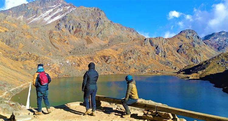 Les trekkers se reposent sur un banc surplombant le lac alpin serein de Gosainkunda et les falaises environnantes.