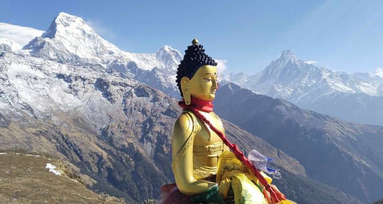 Estatua de Buda dorado con los dramáticos picos del Himalaya cubiertos de nieve de fondo.