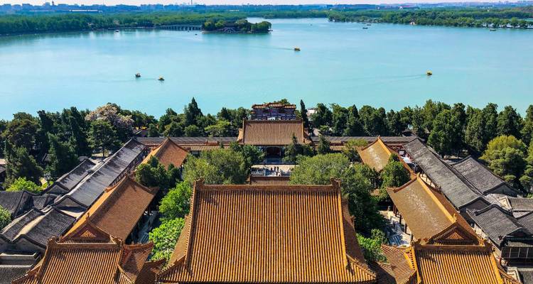 Luftaufnahme der Dächer des Sommerpalastes und des Kunming-Sees mit Booten und der Stadt in der Ferne.