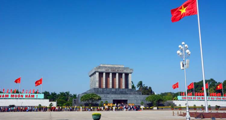 Grote menigte die buiten het Ho Chi Minh-Mausoleum aanschuift op een helder dag met meerdere rode vlaggen die wapperen.