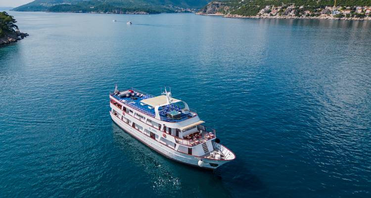Luftaufnahme eines kleinen Kreuzfahrtschiffes, das durch tiefblaue Gewässer der Adria gleitet.