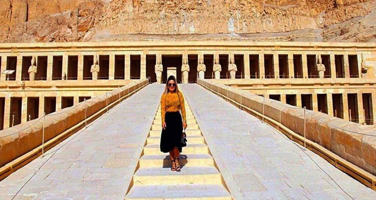 Voyageur posant sur la grand rampe centrale menant au Temple d'Hatchepsout à colonnade, creusé dans une falaise.