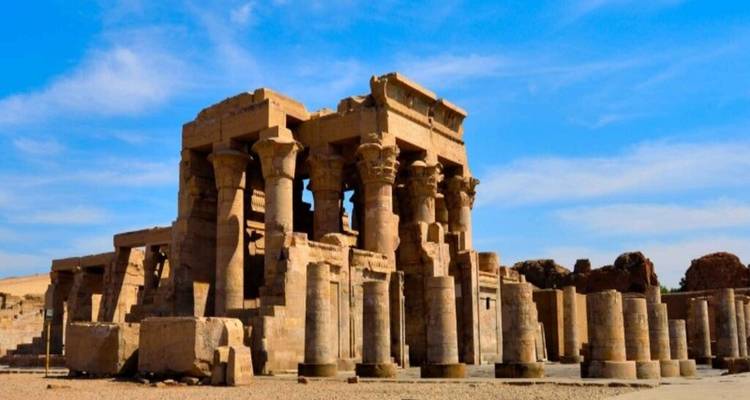Les ruines d'un ancien temple en grès avec de hautes colonnes sous un ciel bleu dégagé dans le désert.