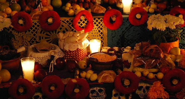 Autel du Jour des Morts chaleureusement éclairé, chargé de bougies, de soucis, de pain, de fruits et de crânes en sucre