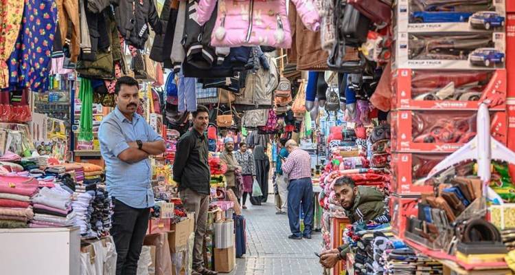 Colorful, crowded alley of Manama Souq brimming with textiles and toys.