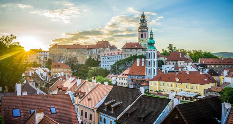 Amanecer radiante sobre los tejados en tonos pastel y el castillo de Cesky Krumlov en una mañana despejada.