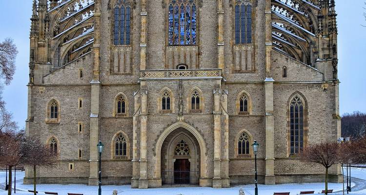 Fachada frontal de la Iglesia de Santa Bárbara en Kutna Hora enmarcada por nieve ligera en el suelo.