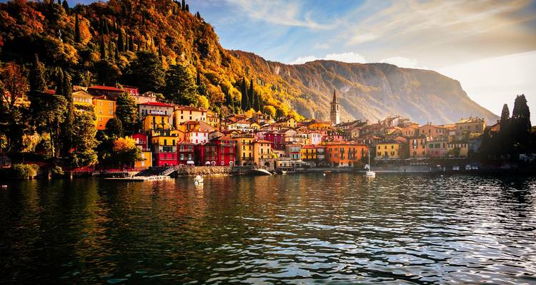Malerisches Dorf Varenna mit leuchtend bemalten Häusern, eingebettet an einem Herbst gefärbten Hügel am Comer See.