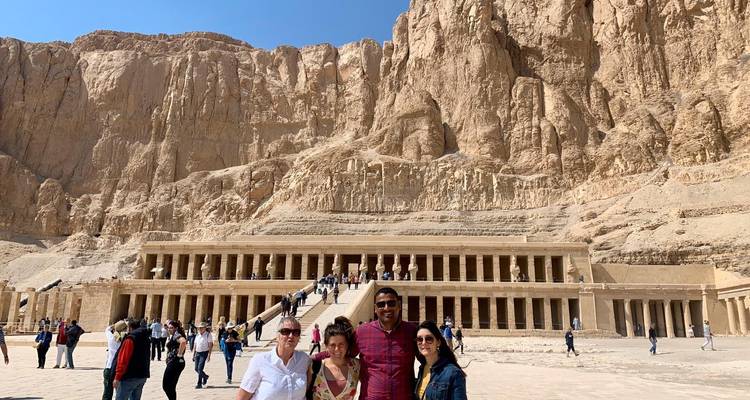 Quatre amis souriants devant le temple emblématique d'Hatchepsout avec ses falaises de grès