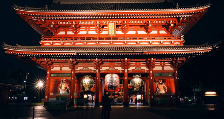 Illuminated main gate of Senso-ji Temple at night with visitors entering